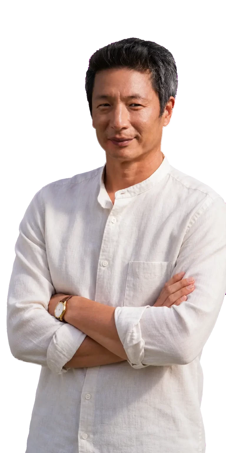 Man standing with arms crossed, wearing a white button-up shirt and a watch, smiling slightly against a black background with pink accents.